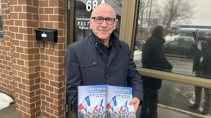 Un homme tient deux cahiers.