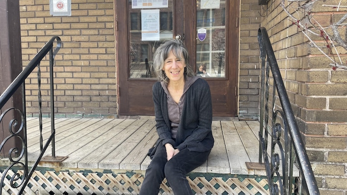 La directrice de l'organisme L'Avant-garde, Connie Bleau. Elle est assise sur un balcon.