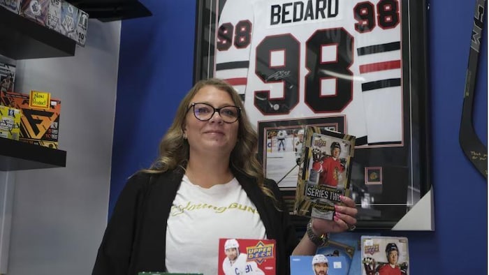 La copropriétaire du magasin 306 Sports Cards à Saskatoon, Stephanie Pettit, tient dans ses mains un paquet contenant les cartes de collection de la recrue du hockey Connor Bedard. 