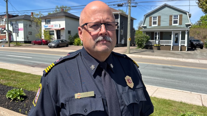 Conrad Landry portant un uniforme de pompier près d'une rue. 
