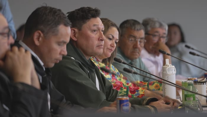 Plusieurs Inuit assis à une table devant des micros.
