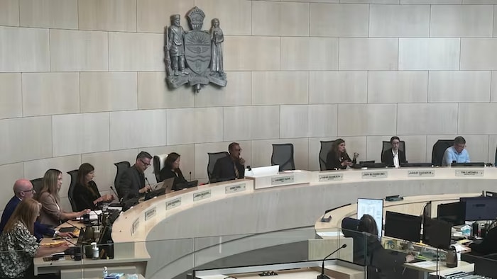 Des conseillers municipaux d'Edmonton sont assis dans une salle de l'hôtel de ville lors d'une réunion.