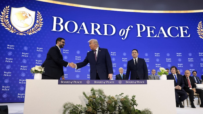 Donald Trump serre la main du cheikh Isa bin Salman bin Hamad Al Khalifa, observés par plusieurs autres, sur une scène.