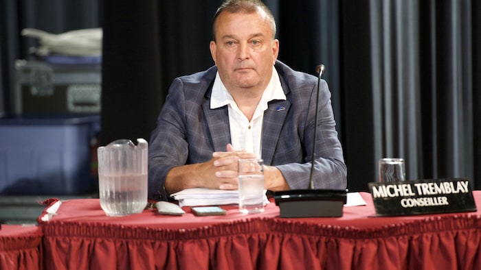 Michel Tremblay est assis à la table du conseil.