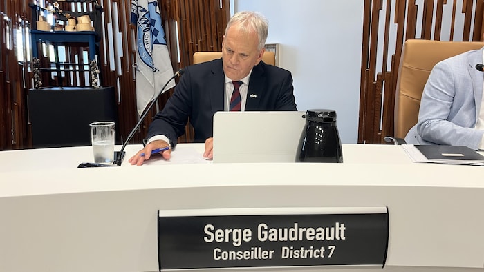 Serge Gaudreault est assis à la table du conseil.