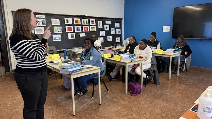 Plusieurs personnes en classes écoutent une femme parler.