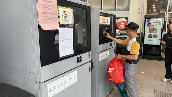 Un homme dépose une canette dans une gobeuse pour la consigner.