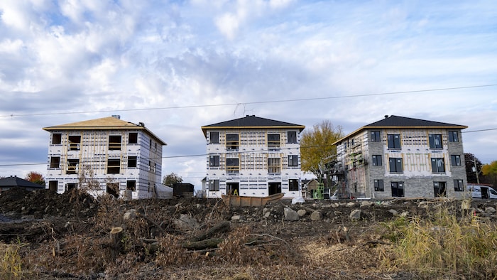 Un chantier de construction pour un développement résidentiel comprenant trois bâtiments à logements multiples en cours de construction.