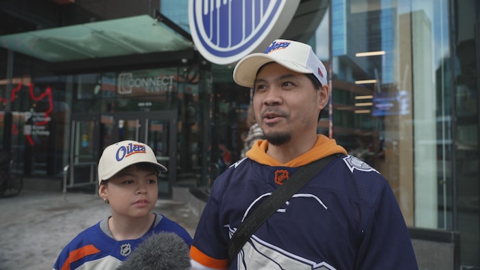 Oliver et son fils sont devant un magasin d'articles des Oilers. 
