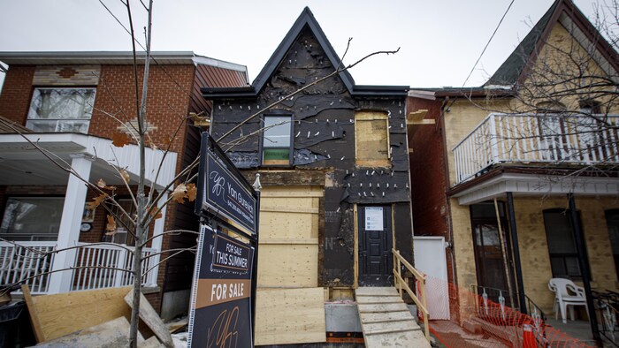 Une maison en construction avec un panneau de vente à l'avant.
