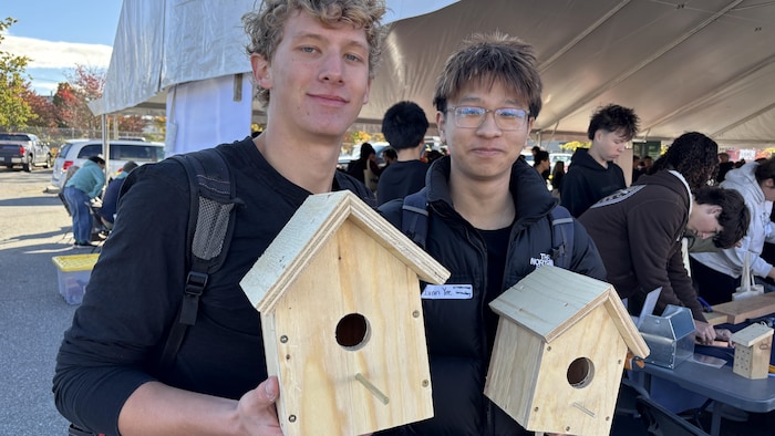 Des jeunes tiennent des nichoirs.