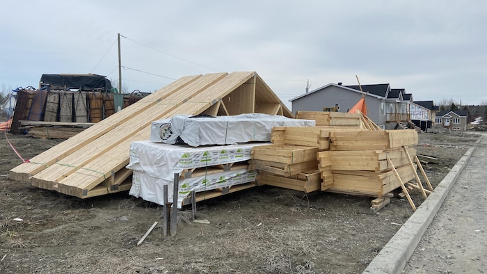 Des matériaux en bois disposés sur un terrain en vue de servir à la construction d'une maison.