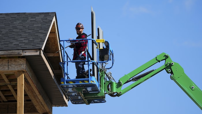 Un ouvrier du bâtiment travaille depuis une plateforme élévatrice dans un nouveau lotissement à Ottawa.
