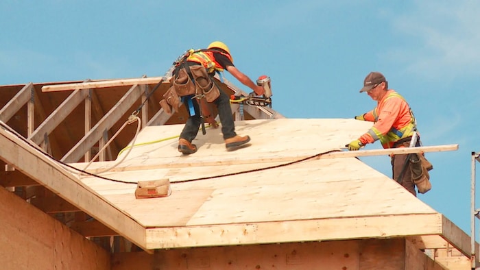 Deux travailleurs sur un toit en construction. 