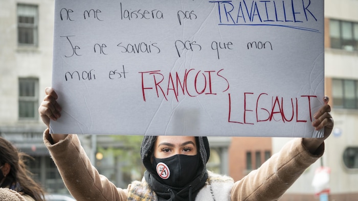 Une femme tient une pancarte qui conteste la loi 21.