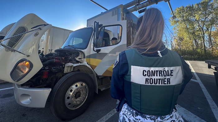 Un contrôleur routier en uniforme regarde un camion lourd