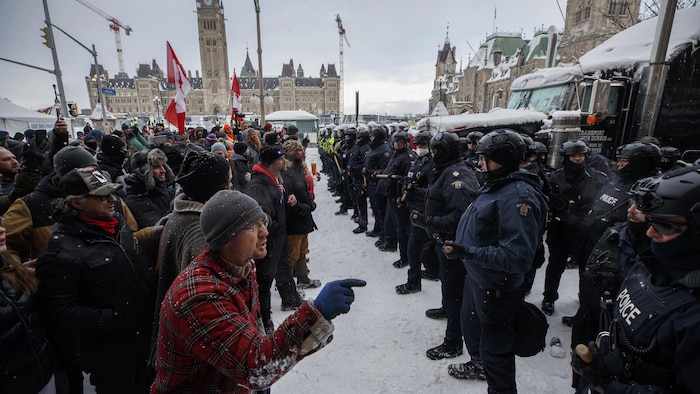 Un groupe de manifestants invectivent des policiers à Ottawa l'hiver.