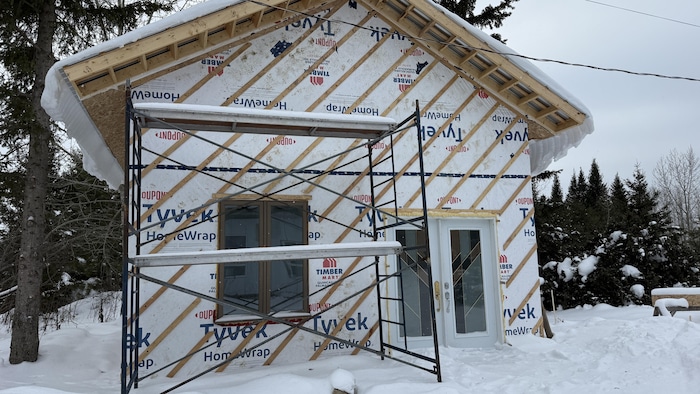 Une vue extérieur d'un petit bâtiment en construction avec des échafaudages.