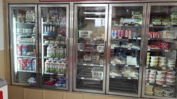 Un frigidaire dans un dépanneur avec plusieurs produits du lait.