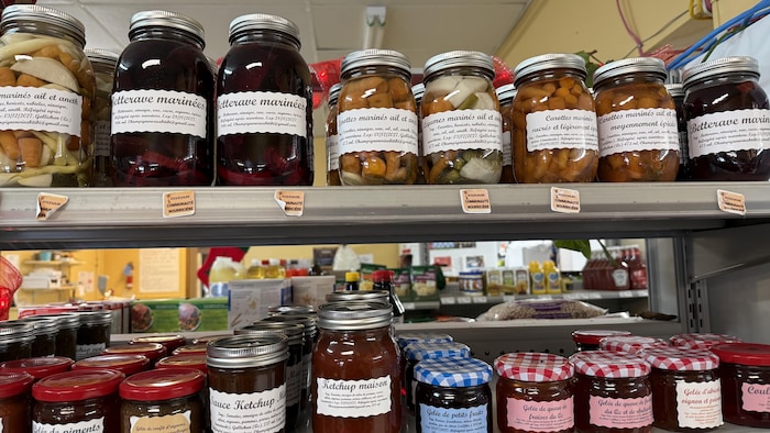 Des conserves de produits locaux sont disposés sur deux tablettes.