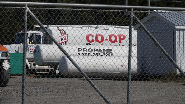 Un camion de propane devant un réservoir de propane. 