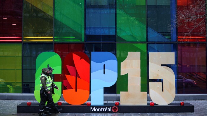 Deux policiers marchent devant l'enseigne de la COP15 au Palais des congrès.