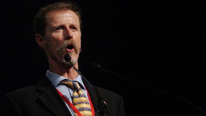 David R. Boyd habla detrás de un micrófono en un escenario.