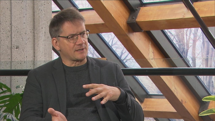 Un homme parle devant un toit vitré.