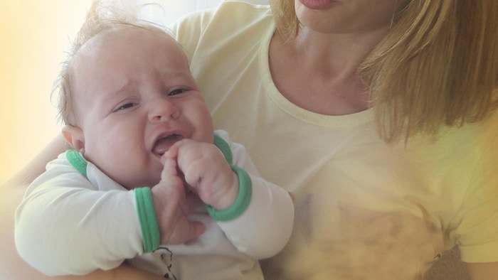 Un bébé dans les bras d'une femme adulte tousse.