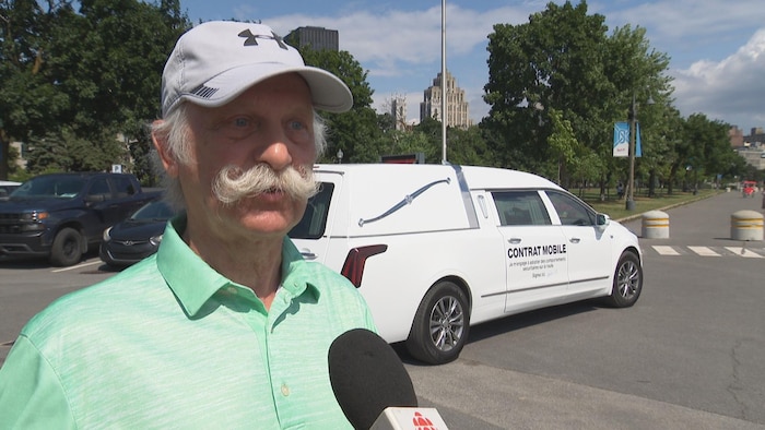 Un homme moustachu parle au micro.