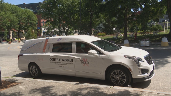 Un corbillard, avec « contrat mobile » inscrit sur la voiture