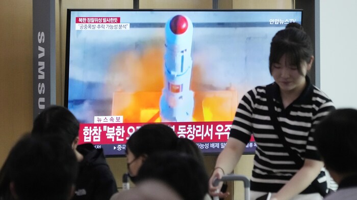 Un écran de télévision diffusant les images du lancement du satellite.