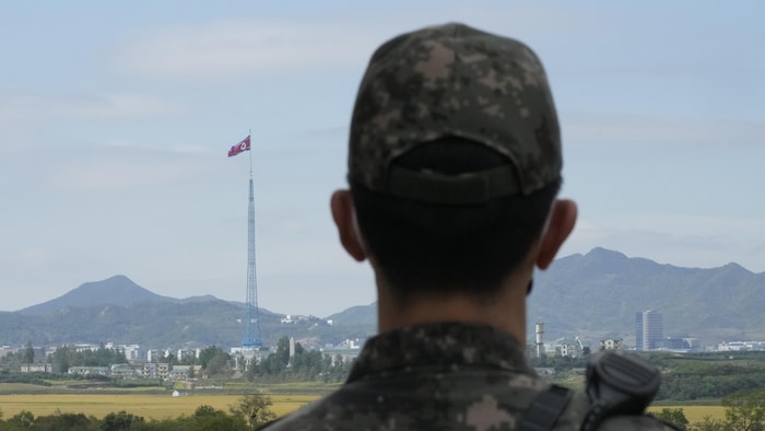 Un soldat regarde un drapeau nord-coréen flotter de l'autre côté de la frontière.