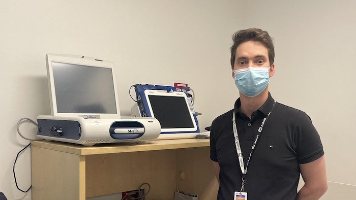Un homme masqué devant des appareils médicaux.