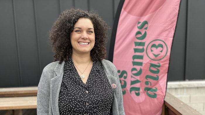 Corinne Larose sur la terrasse sur parc Lévesque devant une affiche des Avenues d'la 3.