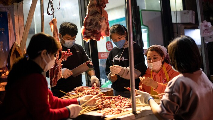 Scène du quotidien dans le marché de Wuhan, où les activités ont récemment repris. Des marchands apprêtent de la viande dans un kiosque de ce marché soupçonné d'être un des premiers lieux d'éclosion du SRAS-CoV-2.