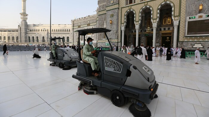 Deux hommes masqués conduisent des machines devant une mosquée. 