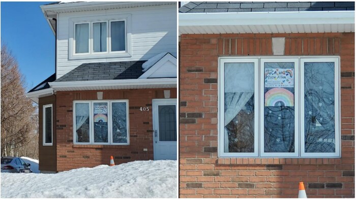 Une maison avec un dessin d'arc-en-ciel accroché dans une fenêtre.