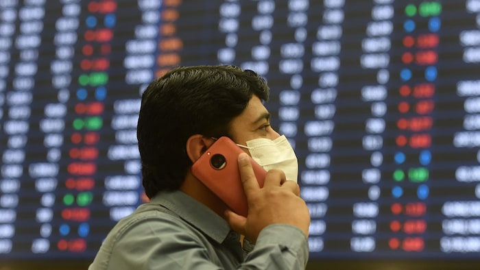 Un investisseur portant un masque parle au téléphone à la Bourse du Pakistan.