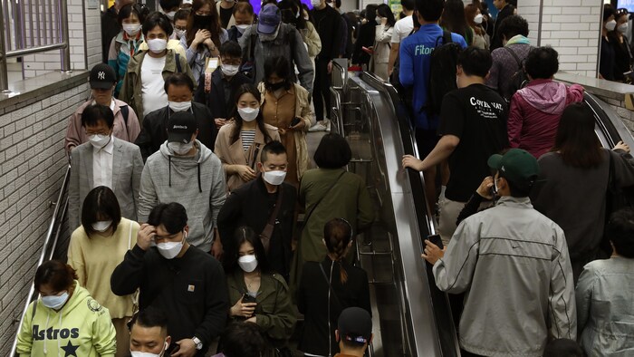 Plusieurs personnes portant des masques médicaux montent et descendent des escaliers dans le métro de Séoul, en Corée du Sud.