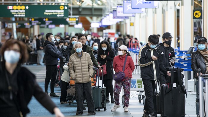 مسافرون في مطار فانكوفر الدولي في مقاطعة بريتيش  كولومبيا في أقصى غرب كندا يرتدون كمامات واقية
