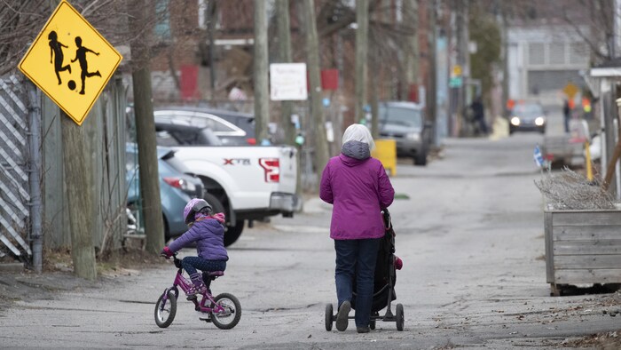 Une femme se promène avec de jeunes enfants dans une ruelle de Montréal.