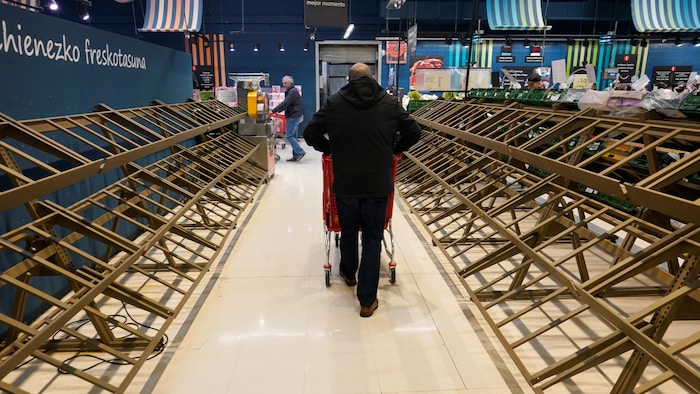 Un homme passe devant des étagères vides dans un supermarché, dans la ville basque de Guernica, en Espagne, le 13 mars 2020.