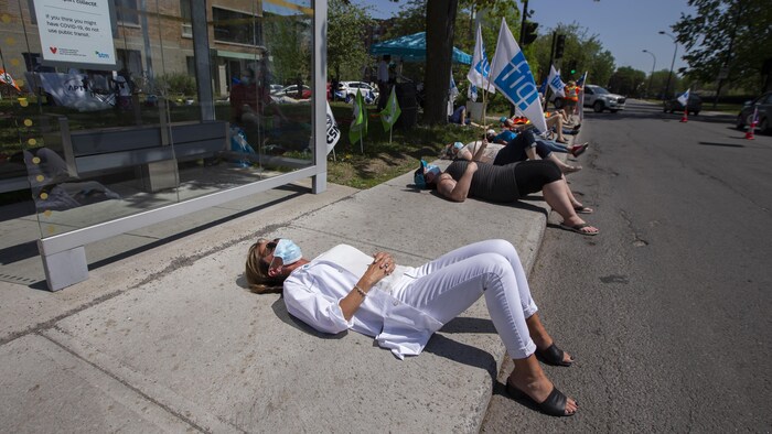 Des femmes allongées sur le dos sur un trottoir en guise de manifestation.