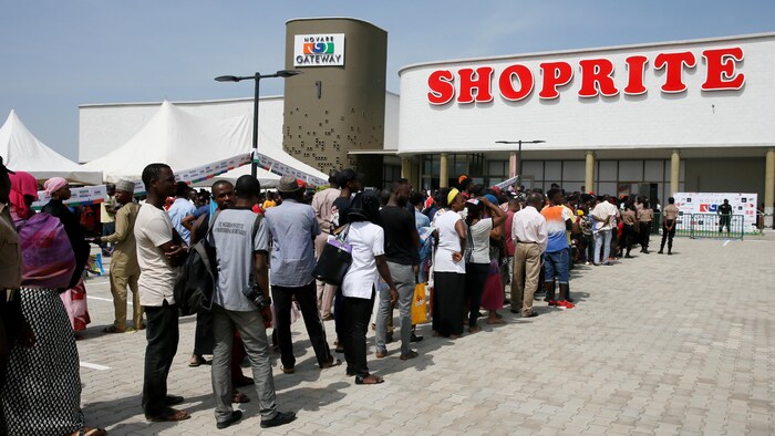 Des dizaines de Nigérians font la file devant un commerce.