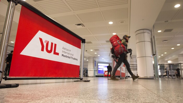 Un homme marche dans l'aéroport Montréal-Trudeau avec un immense sac-à-dos sur son épaule droite.