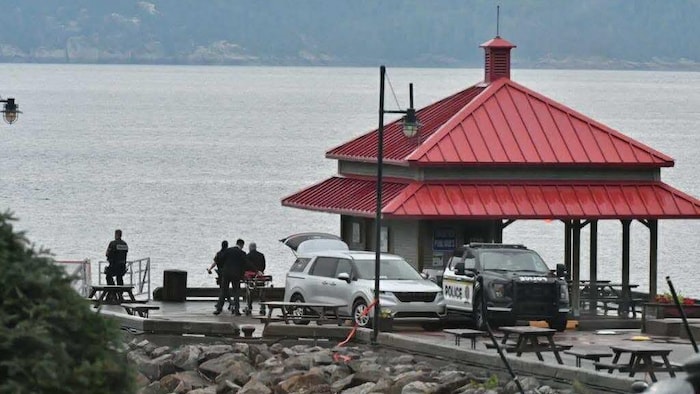 Des policiers transportent un corps sur le quai de L'Anse-Saint-Jean.