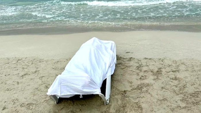 Una sábana cubre un cuerpo en una playa.