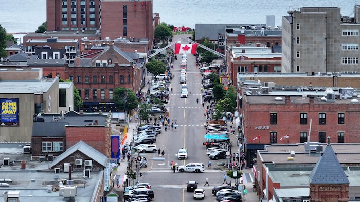 Le cortège funèbre remonte une rue sous un drapeau canadien.