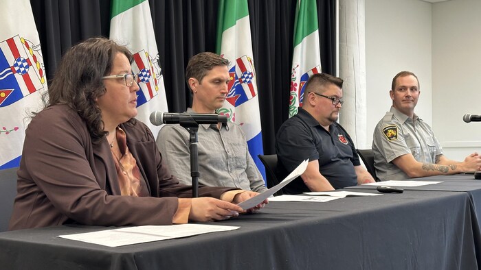 Quatres personnes assises à une table lors d'une conférence de presse.
